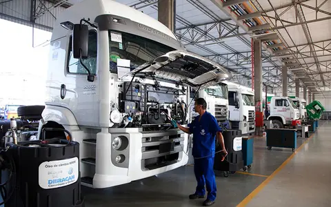 Caminhão com a cabine basculada recebendo manutenção em oficina